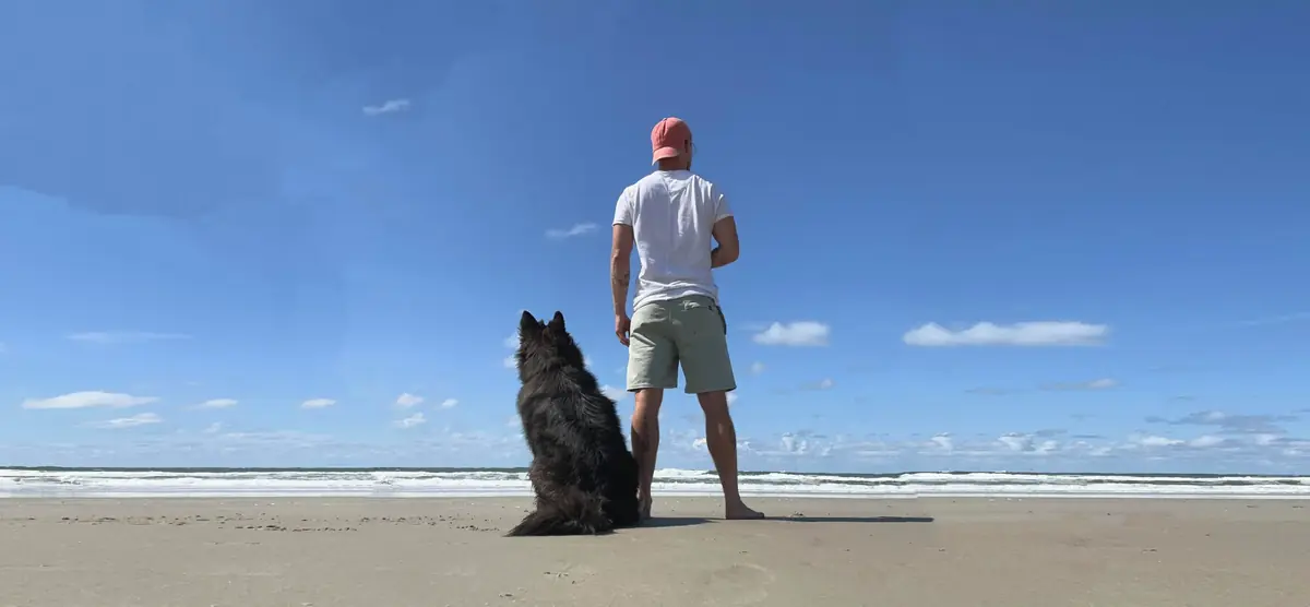 Patrick and Balou on a beach, seen from behind, looking at the sea